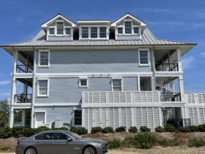 Grand blue three-story coastal home, Topsail, with balconies and shutters.