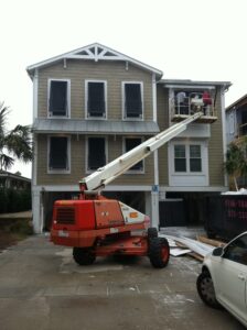 Boom lift workers repair Topsail beach house hurricane shutters.