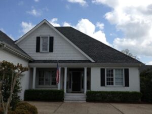 Classic white two-story home with dark shutters, prominent gable, and welcoming porch.
