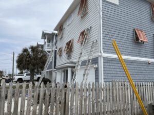 Myrtle Beach house renovation with ladders and hurricane shutters.