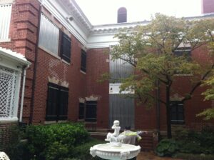 Wilmington historic building, silver shutters, dry fountain, and lush courtyard tree.
