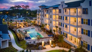 Myrtle Beach luxury complex: illuminated pool, hurricane shutters at twilight.