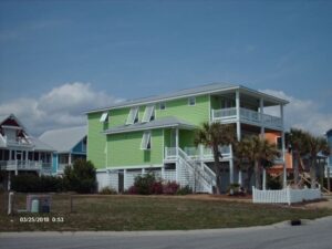 Lime-green Topsail beach house, open white hurricane shutters.
