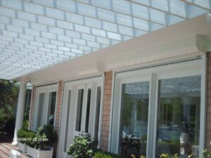 Modern white building, pergola, glass doors, hurricane shutters.