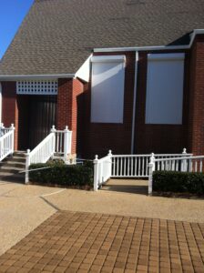 Coastal brick community building with white hurricane shutters.