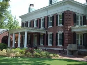 Stately brick home, grand portico, dark impact shutters, Wilmington.
