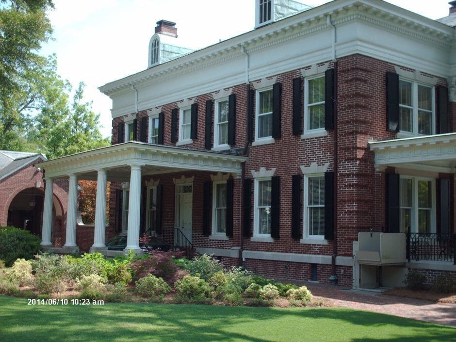Stately brick home, grand portico, dark impact shutters, Wilmington.