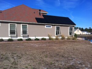 Modern tan Wilmington home with solar panels and hurricane shutters.