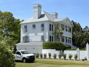 White Southern Colonial home with black hurricane shutters, F-150.