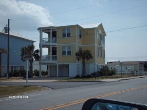 Yellow elevated beach house with white trim on a sunny day.