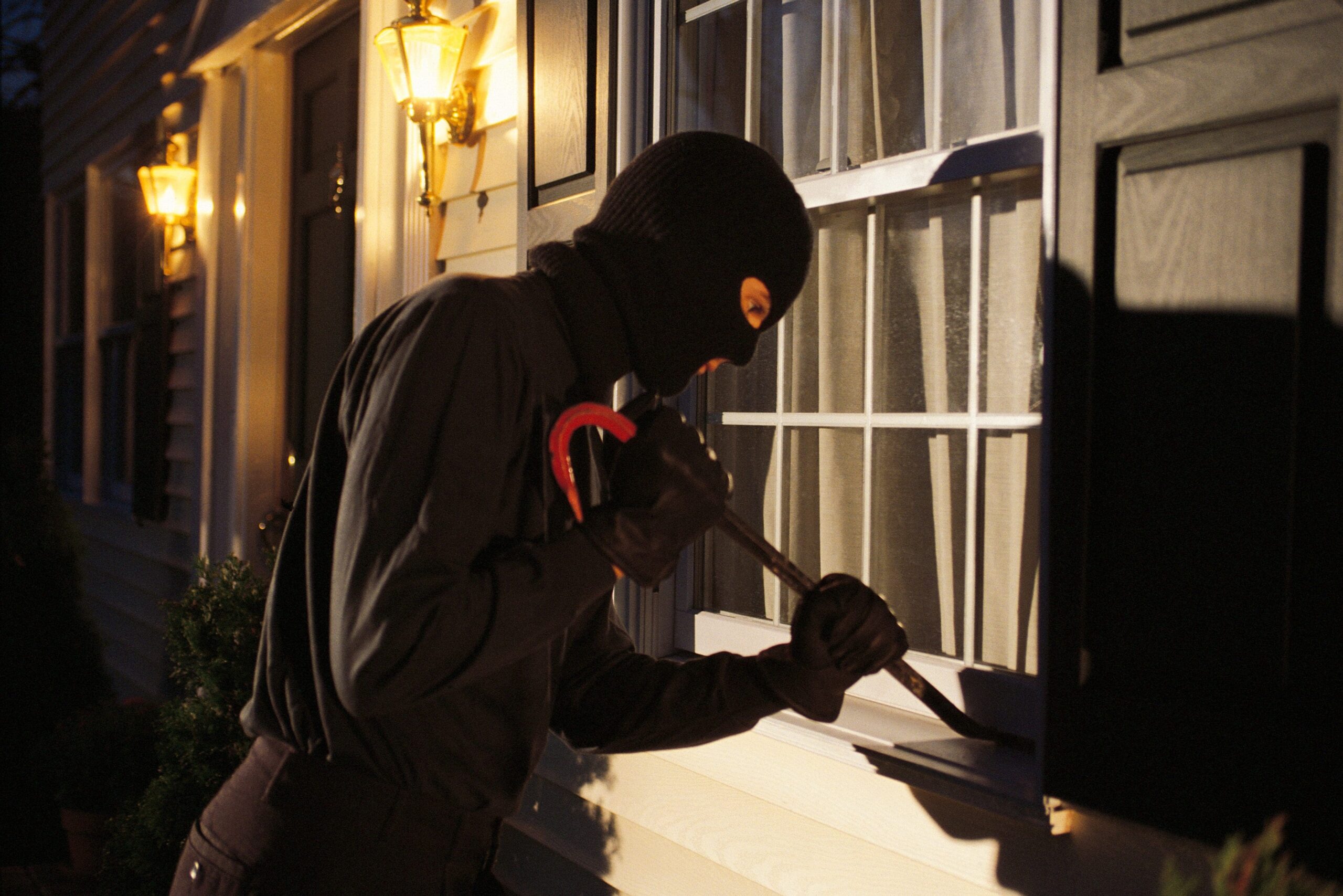Burglar pries window: wilmington home security - american hurricane shutters Wilmington home security: masked burglar prying window with crowbar.