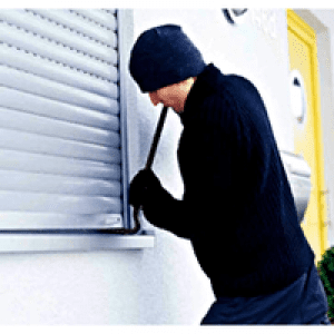 Burglar prying hurricane shutter with crowbar.