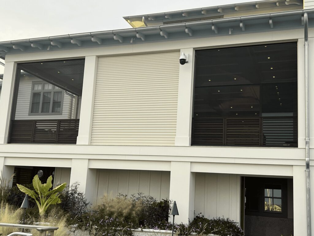 Modern coastal home exterior with hurricane shutters and screens.