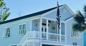Light blue coastal home with Thin Blue Line flag.