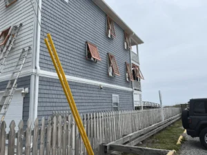 Hurricane shutters on coastal home, wilmington beach - american hurricane shutters Gray shingle beach house with open hurricane shutters, Wilmington Beach.