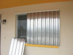 Installing corrugated hurricane shutters on a coastal home window.
