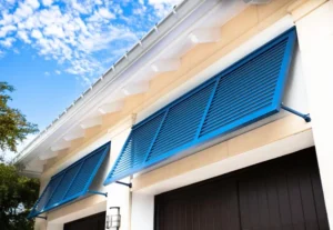 Vibrant blue louvered hurricane shutters on a beige stucco garage.