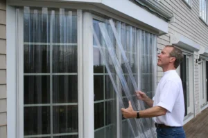 Man installing clear hurricane shutters for Wilmington home storm protection.