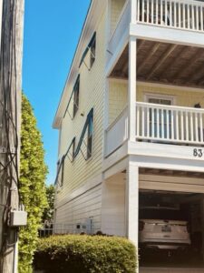 Yellow multi-story home with dark Bahama hurricane shutters.