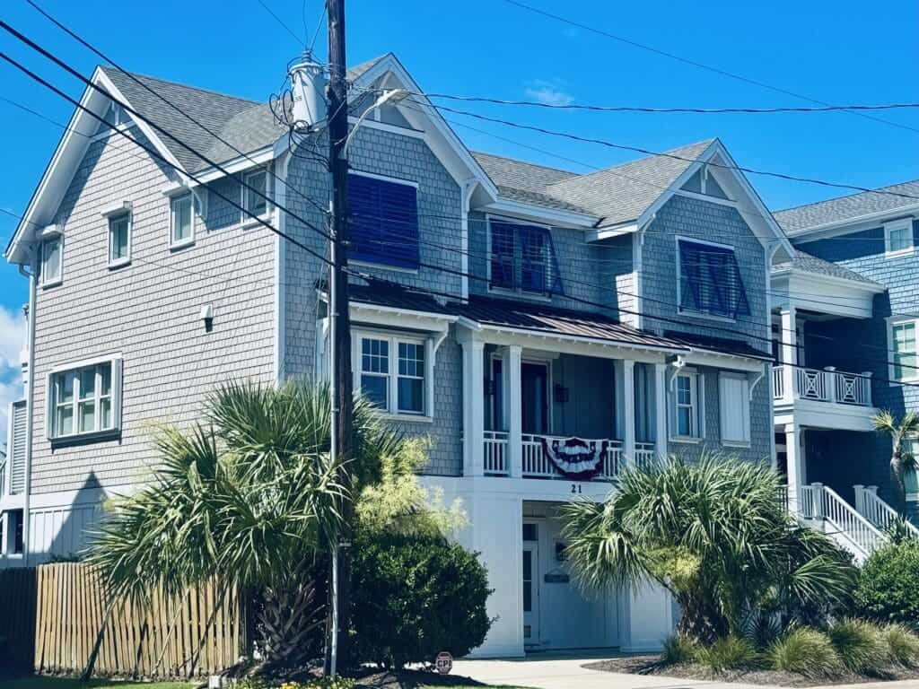 North Topsail home featuring blue Bahama and white accordion hurricane shutters by AHS, providing storm protection for