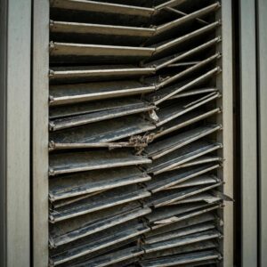 Close-up of a jammed accordion shutter showing debris and corrosion
