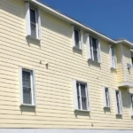 White accordion shutters installed on the balcony of a multi-story vacation rental in Carolina Beach NC.