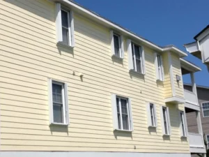 White accordion shutters installed on the balcony of a multi-story vacation rental in Carolina Beach NC.